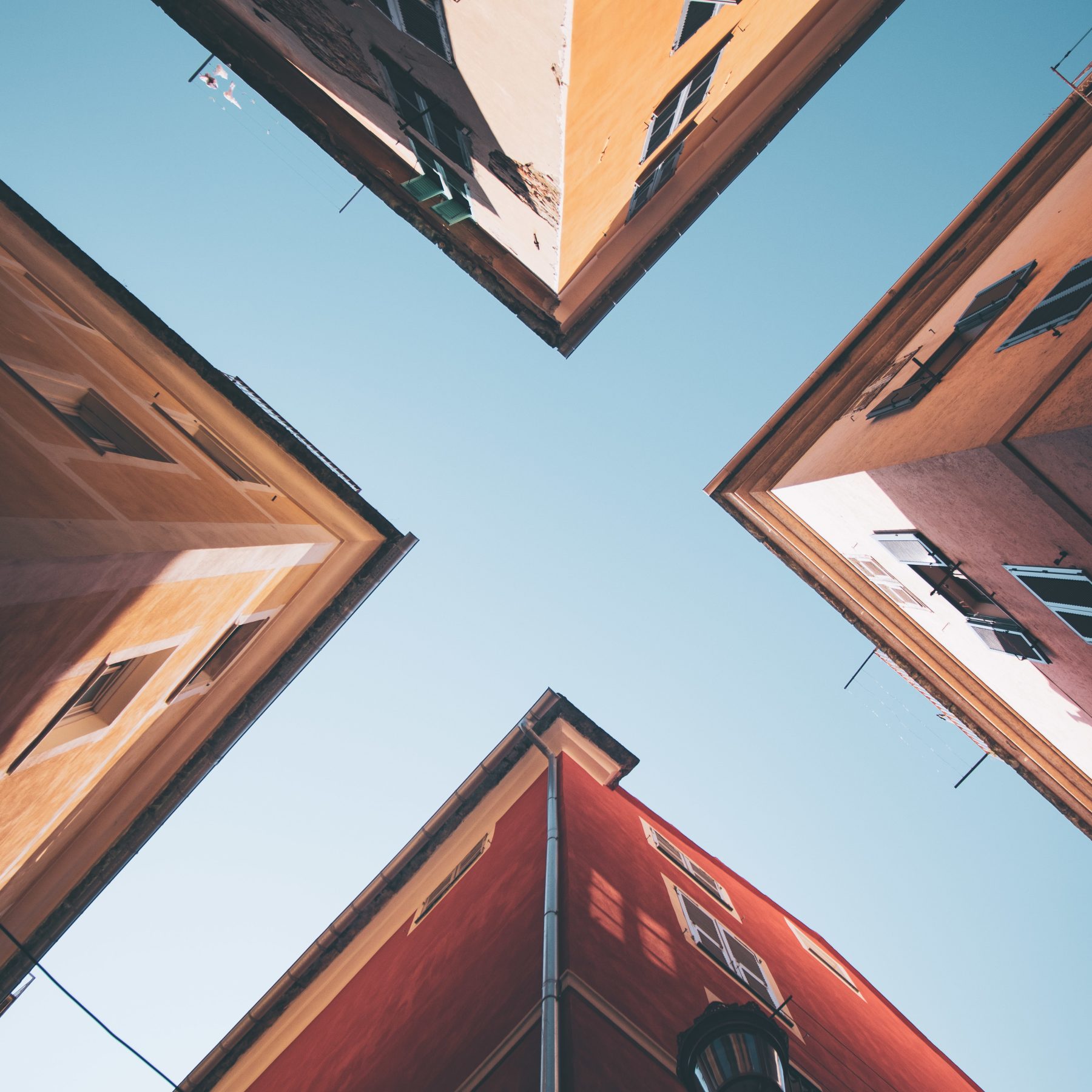 A low angle shot of four buildings under the blue sky
